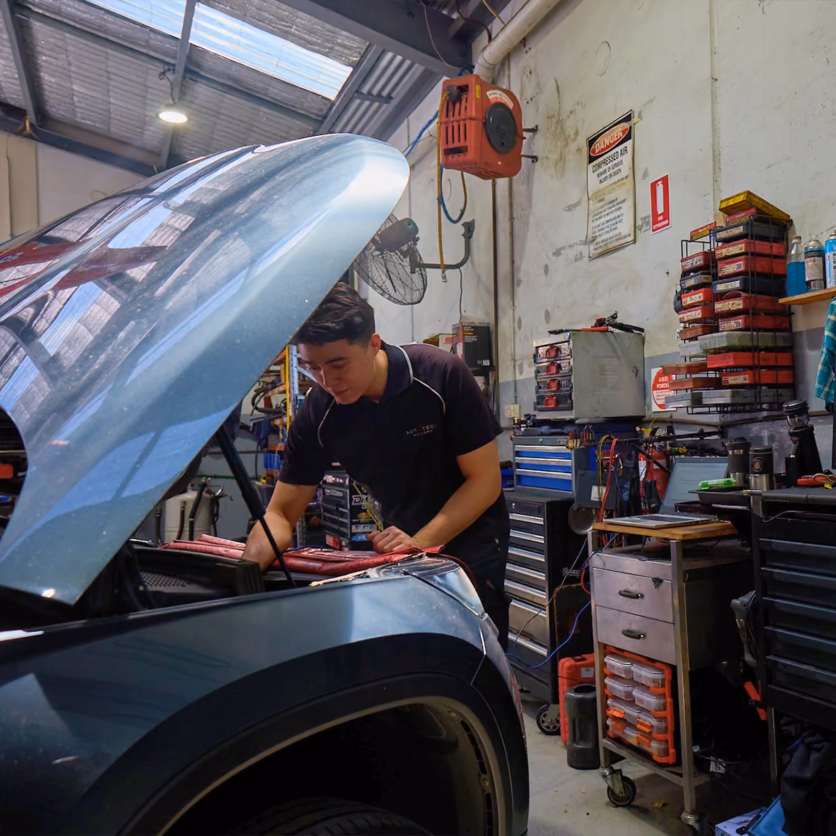 Mechanic working on car in workshop with diagnostic setup.