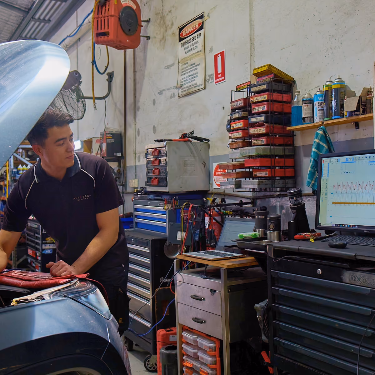 Technician reviewing diagnostic data on computer during vehicle inspection.