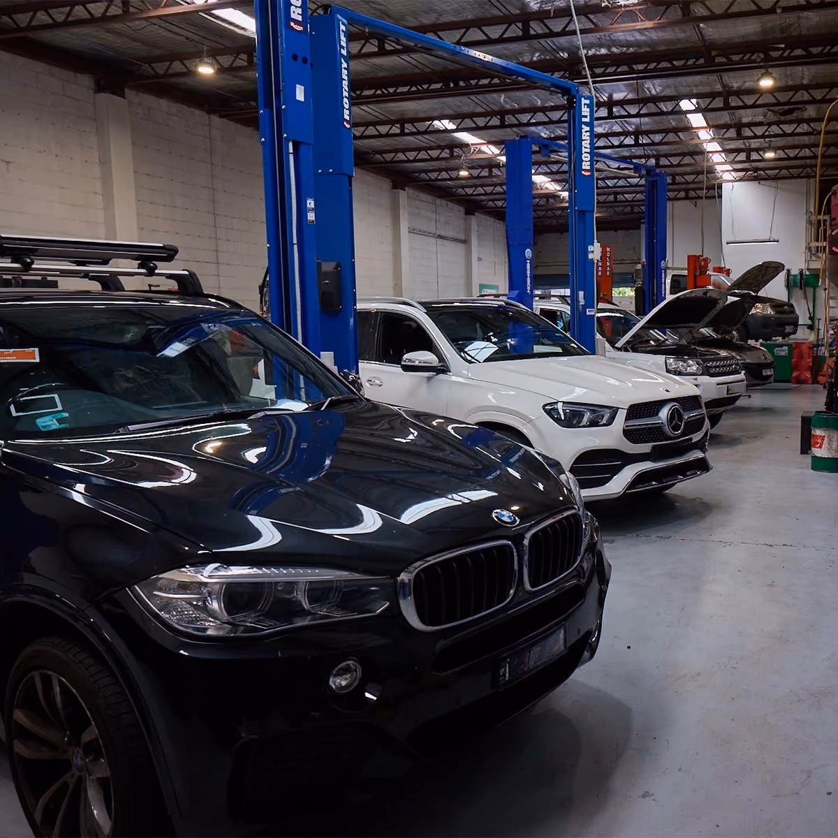 Busy workshop floor with multiple vehicles being inspected and serviced .