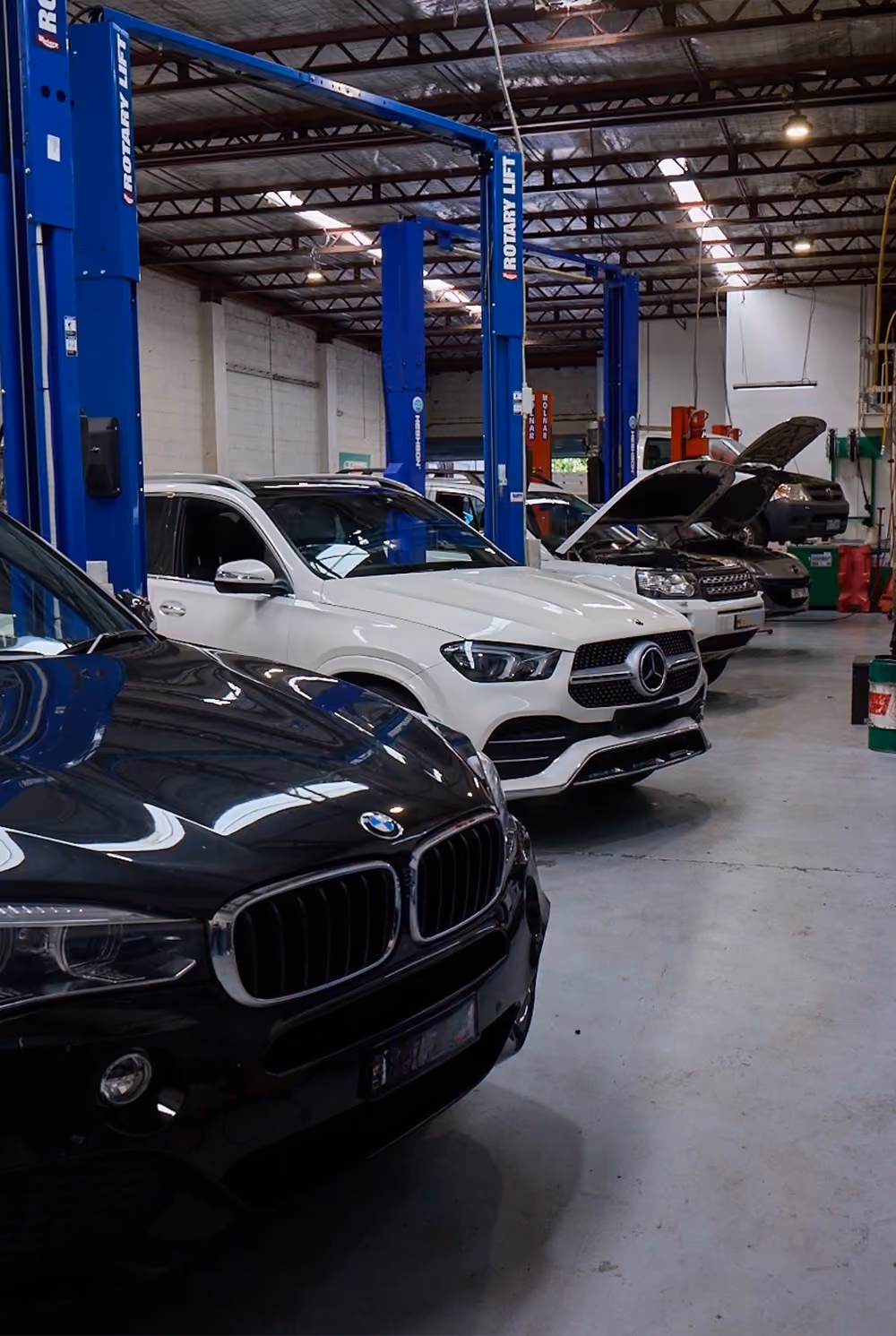 Multiple vehicles being serviced inside workshop.