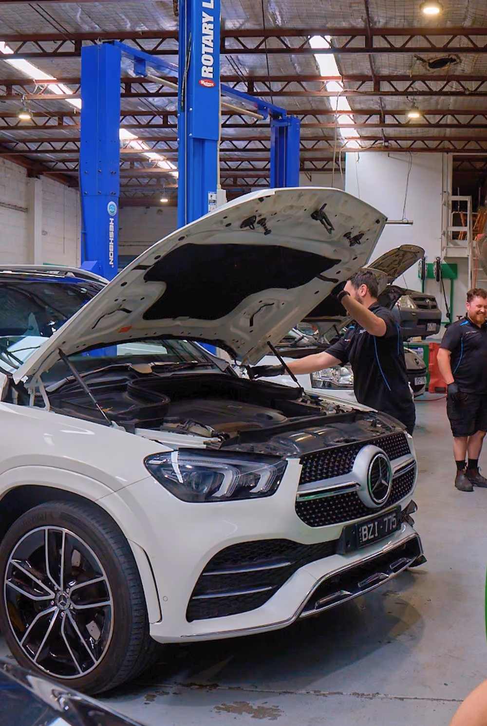 Mechanic servicing Mercedes vehicle in workshop.