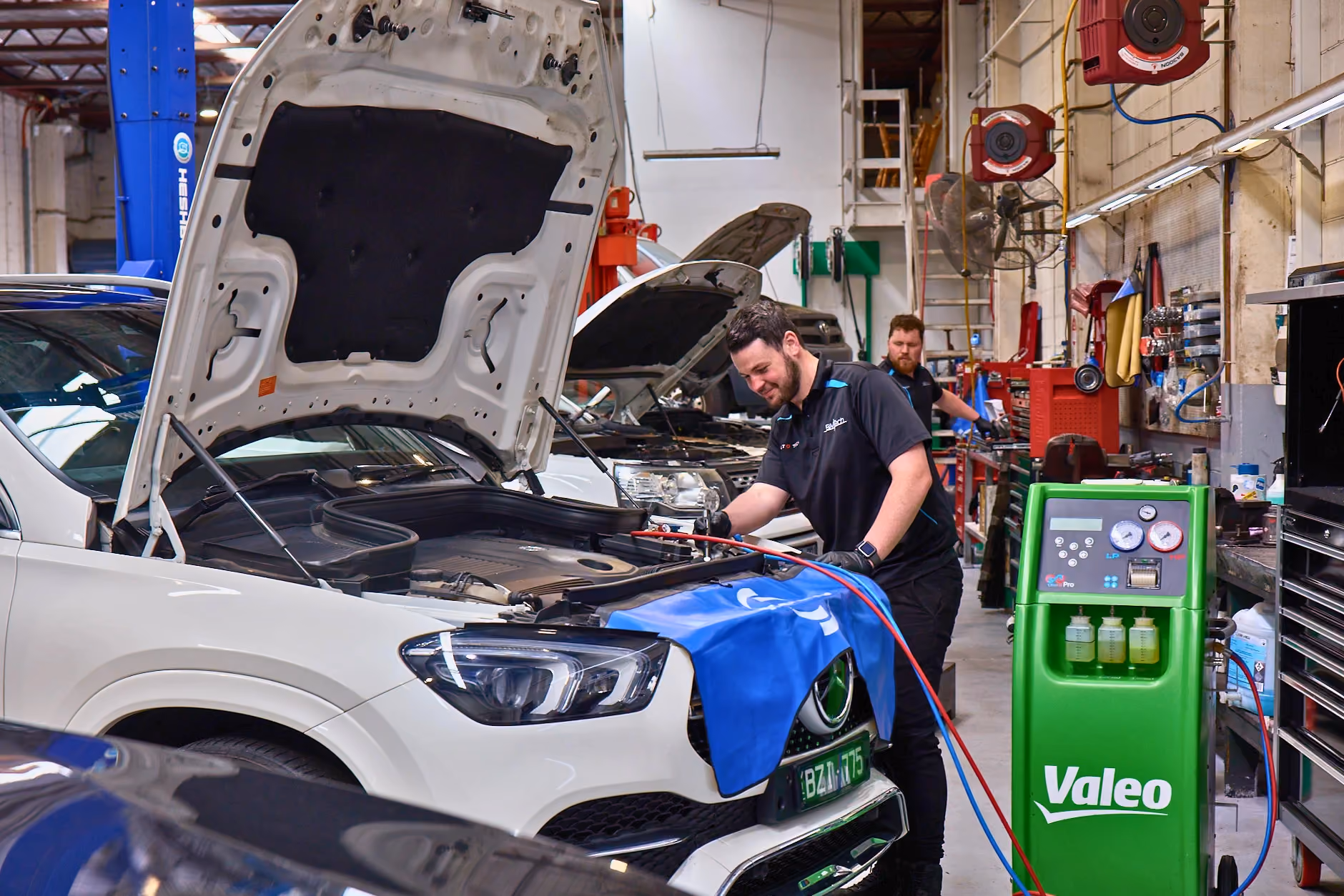 Technician performing repair service on a Mercedes in a workshop.