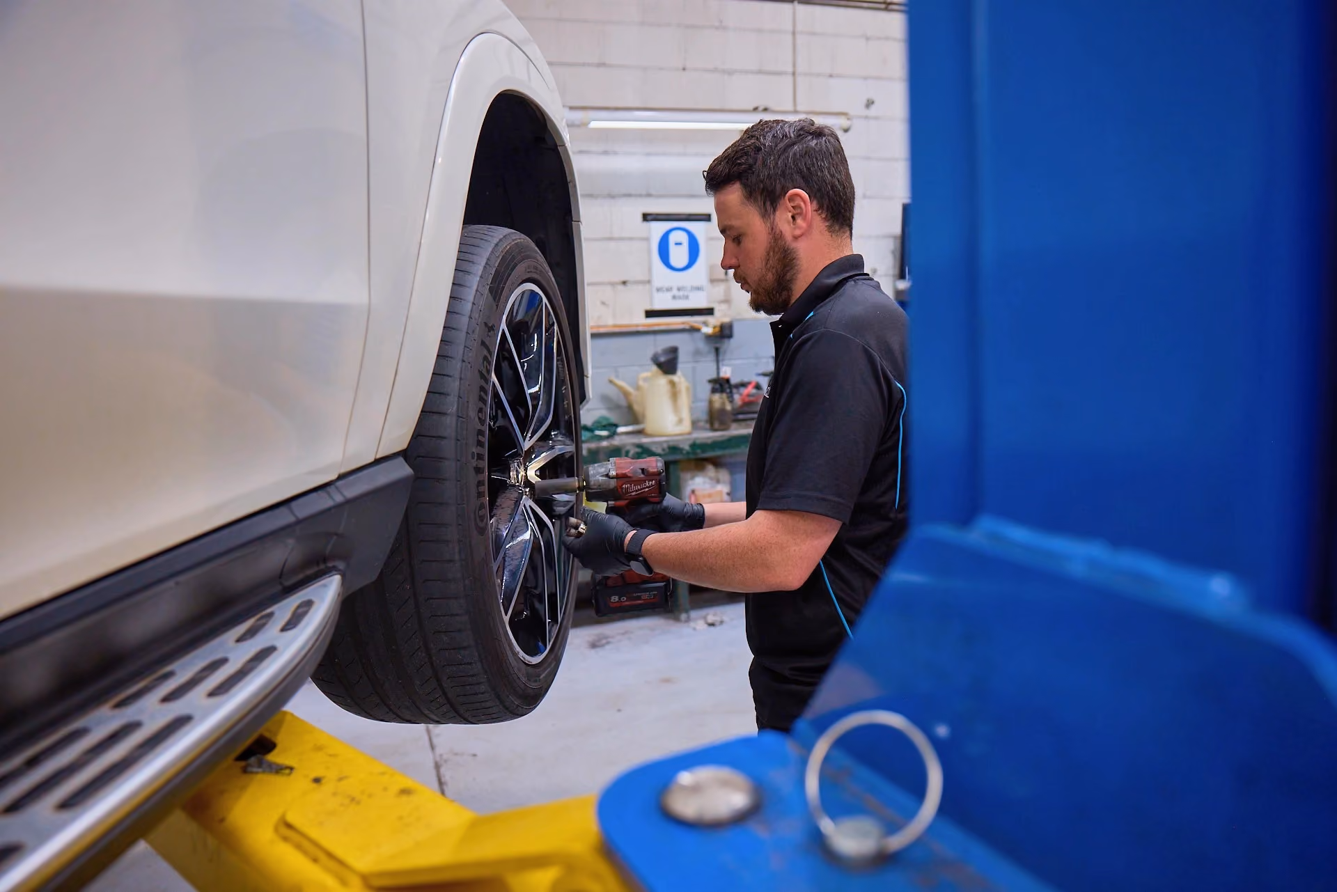 Technician performing wheel and brake maintenance on a European vehicle.
