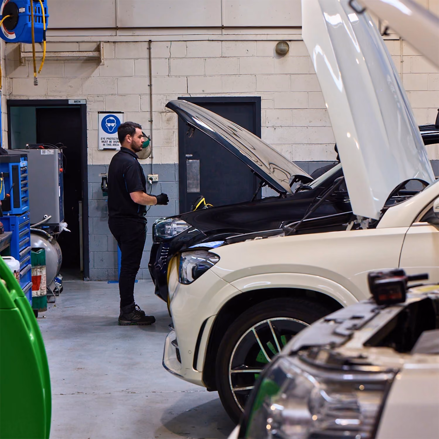Automotive technician performing diagnostics on a Lexus vehicle using a computer workstation inside a professional workshop.