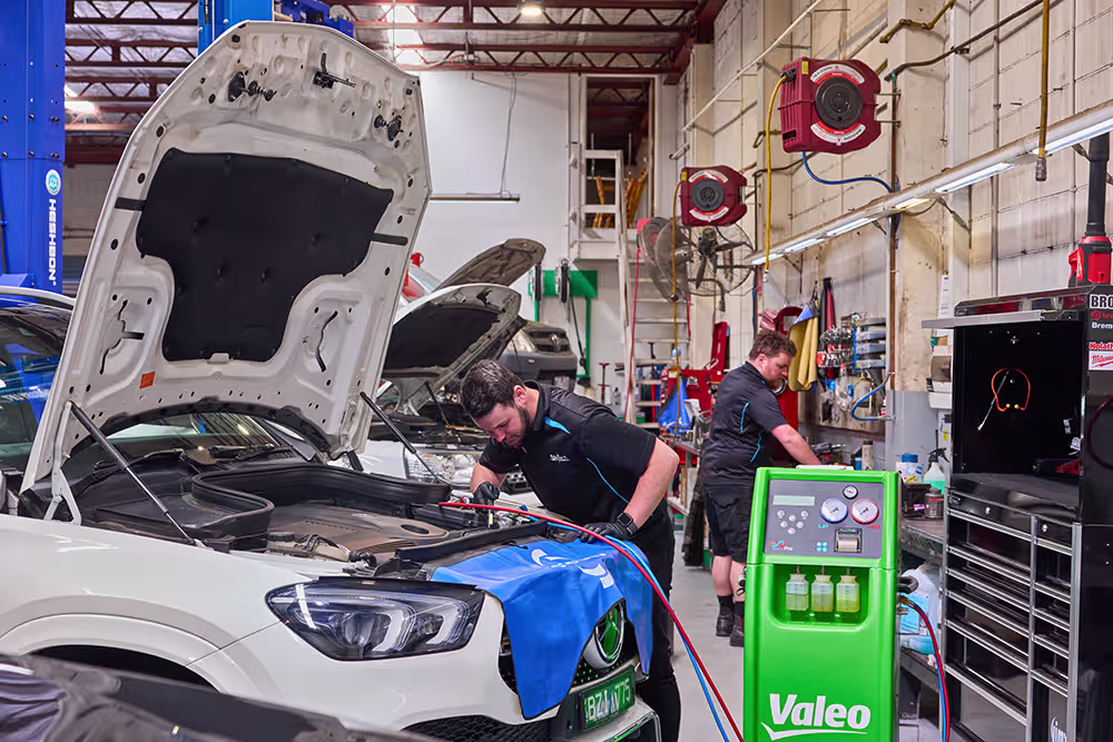 Technicians servicing a European vehicle in a specialist automotive workshop.