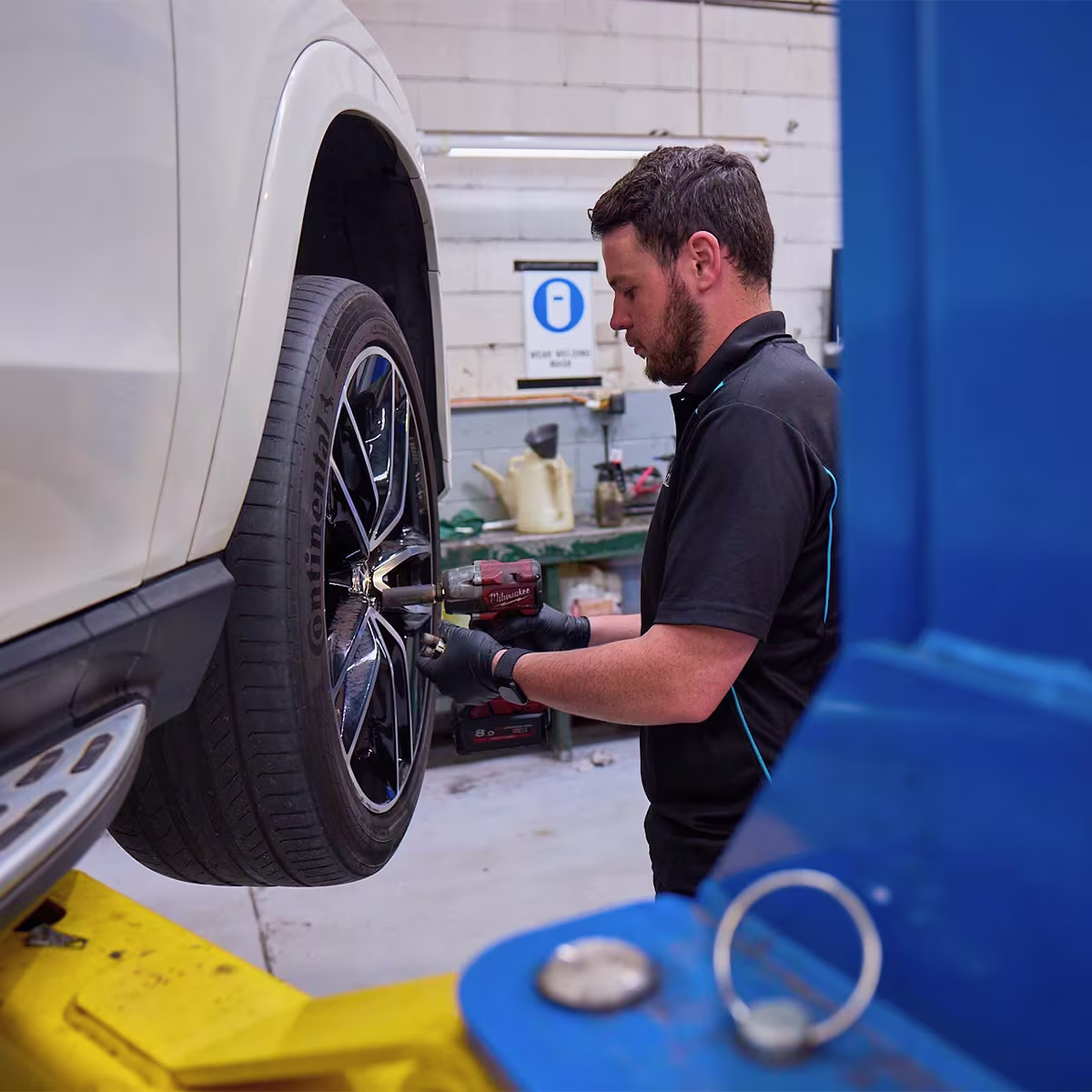 Close-up of mechanic working on tyre and wheel assembly.