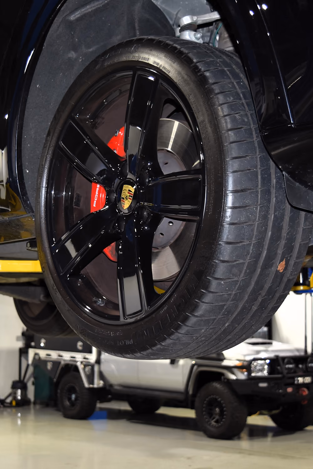 Technician inspecting brake disc and caliper during car service.