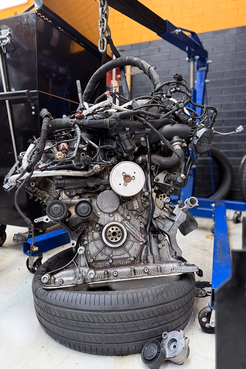 Mechanic diagnosing vehicle engine using computer in workshop.