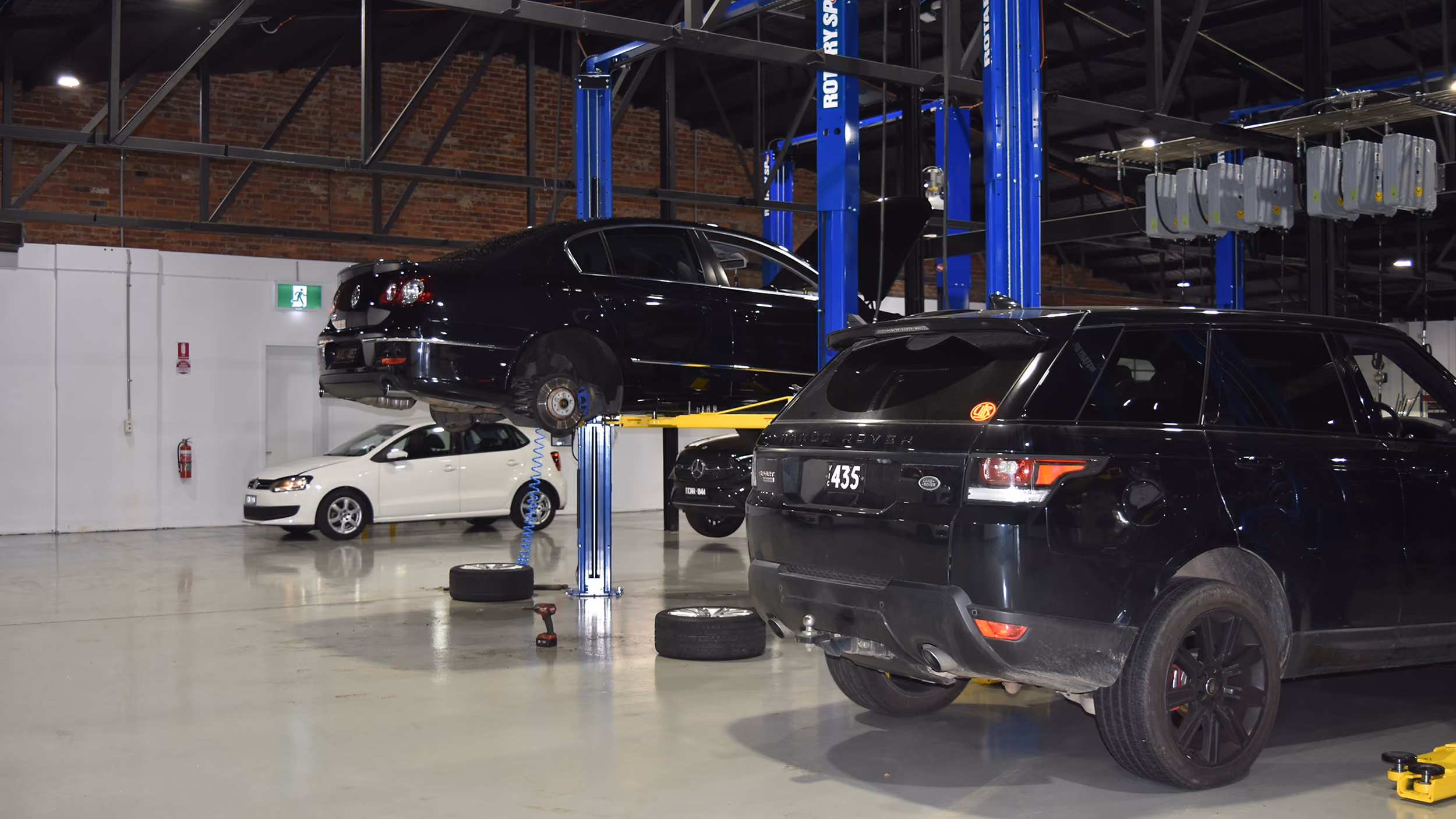 Range Rover and Volkswagen on hoists in the workshop.