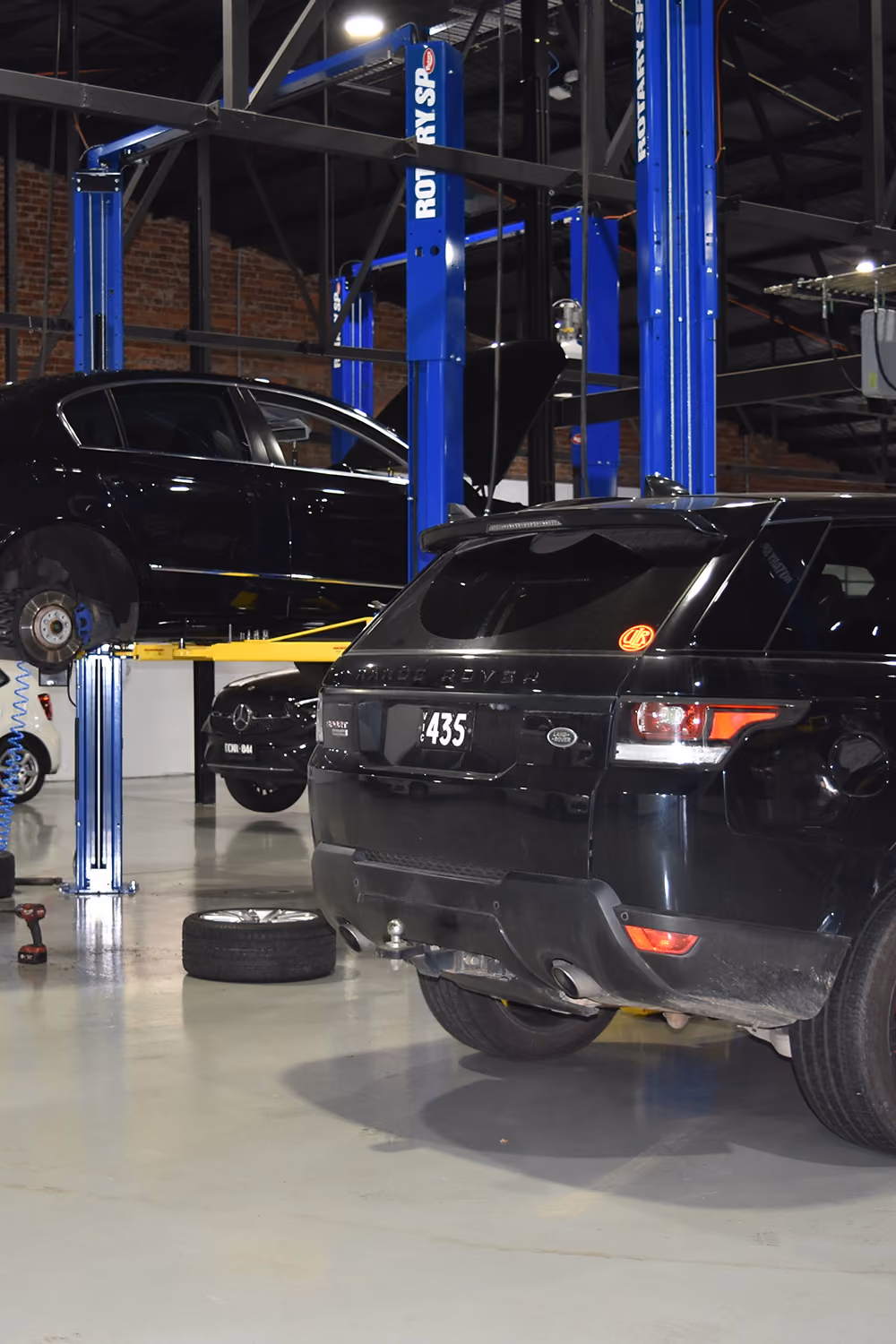 Range Rover and Volkswagen on hoists in the workshop.