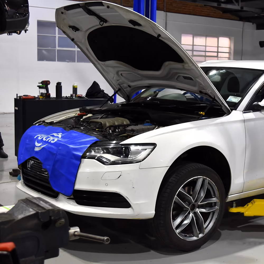Technician performing an oil change under the vehicle bonnet.