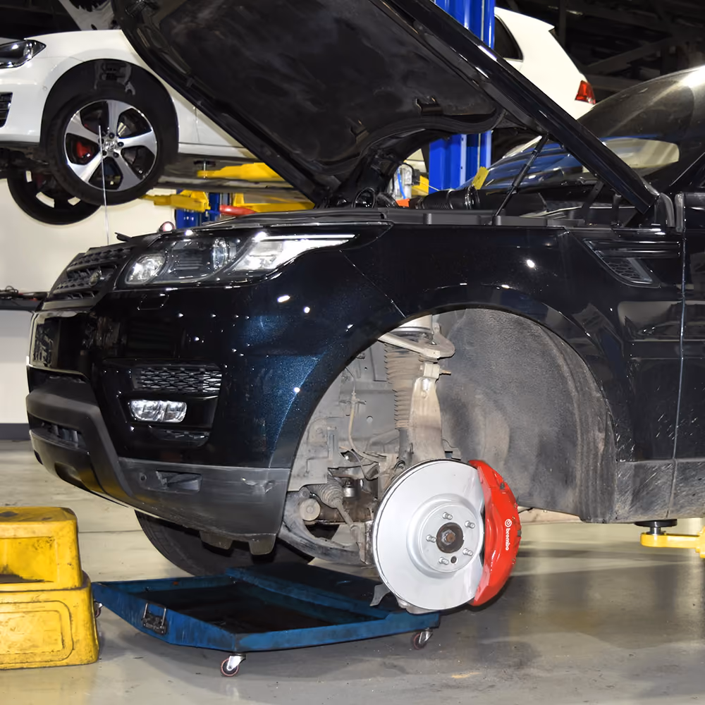 Technician inspecting the brakes on a Range Rover in the workshop.