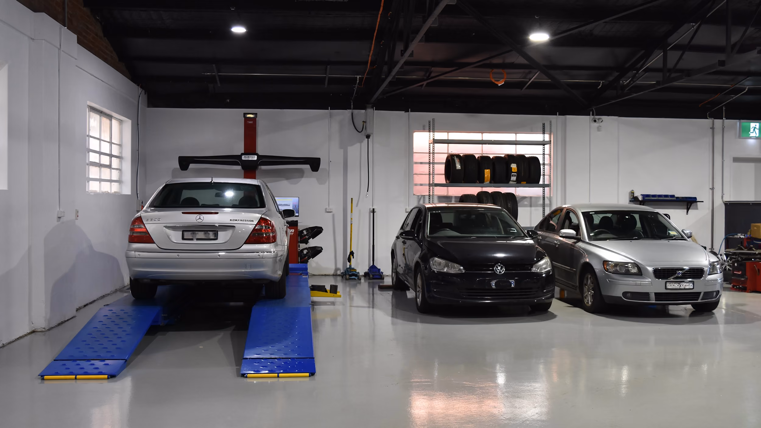 Mercedes, Volkswagen and Volvo on hoists in the workshop.