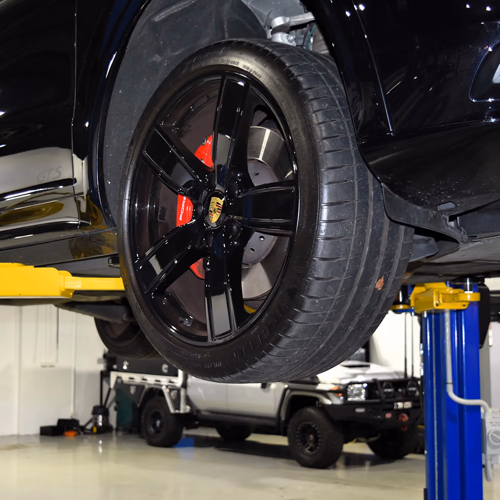 Porsche wheel and tyre being inspected and fitted in the workshop.