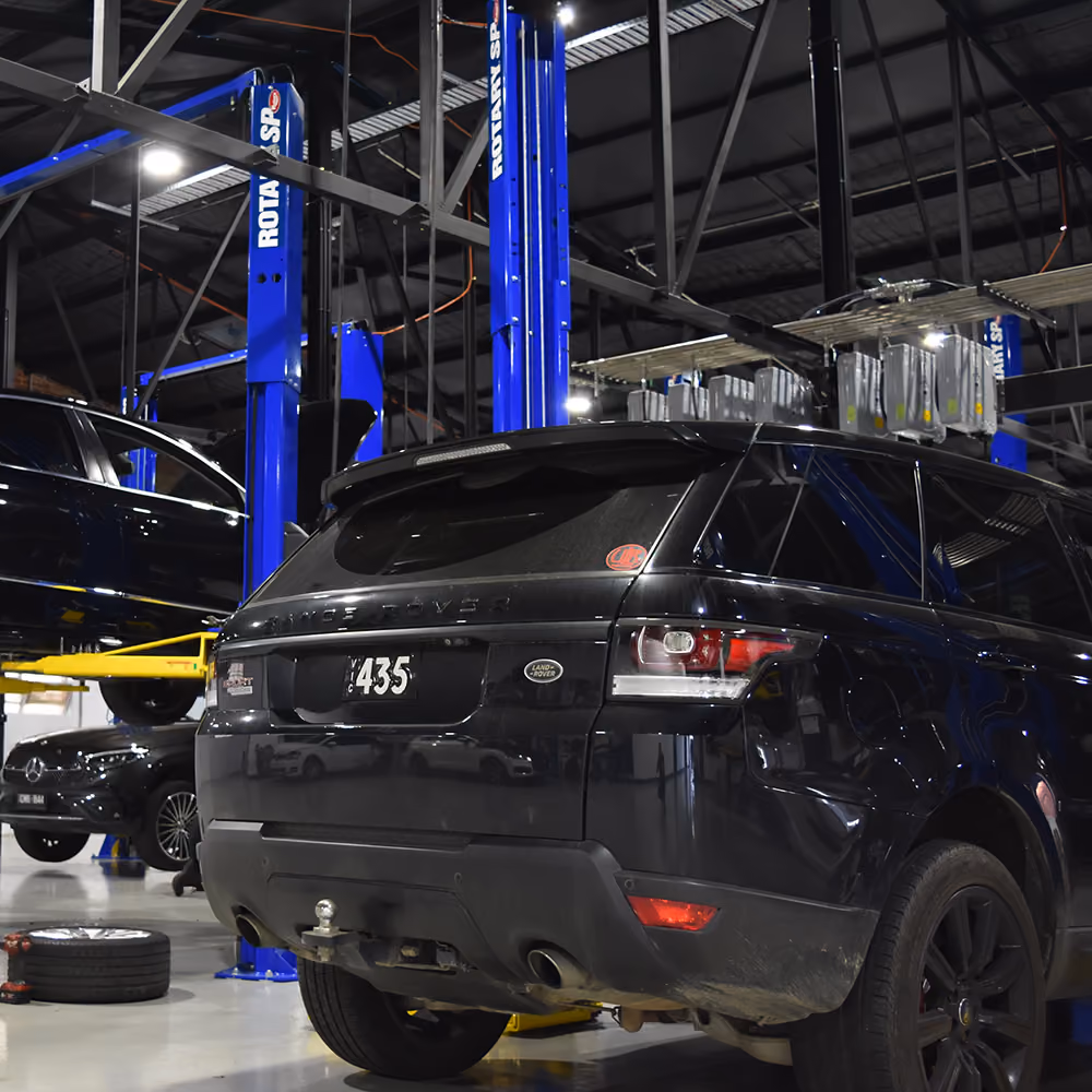 Range Rover and Volkswagen raised on workshop hoists.