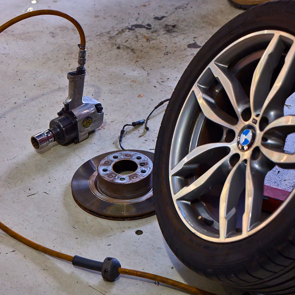 Technician working on a vehicle wheel and tyre in the service bay.