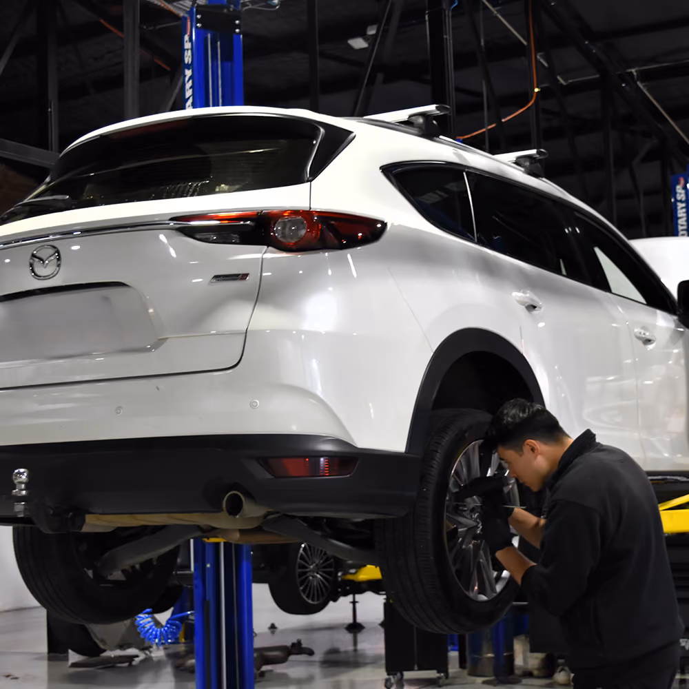 Technician servicing the brakes on a Mazda in the workshop.