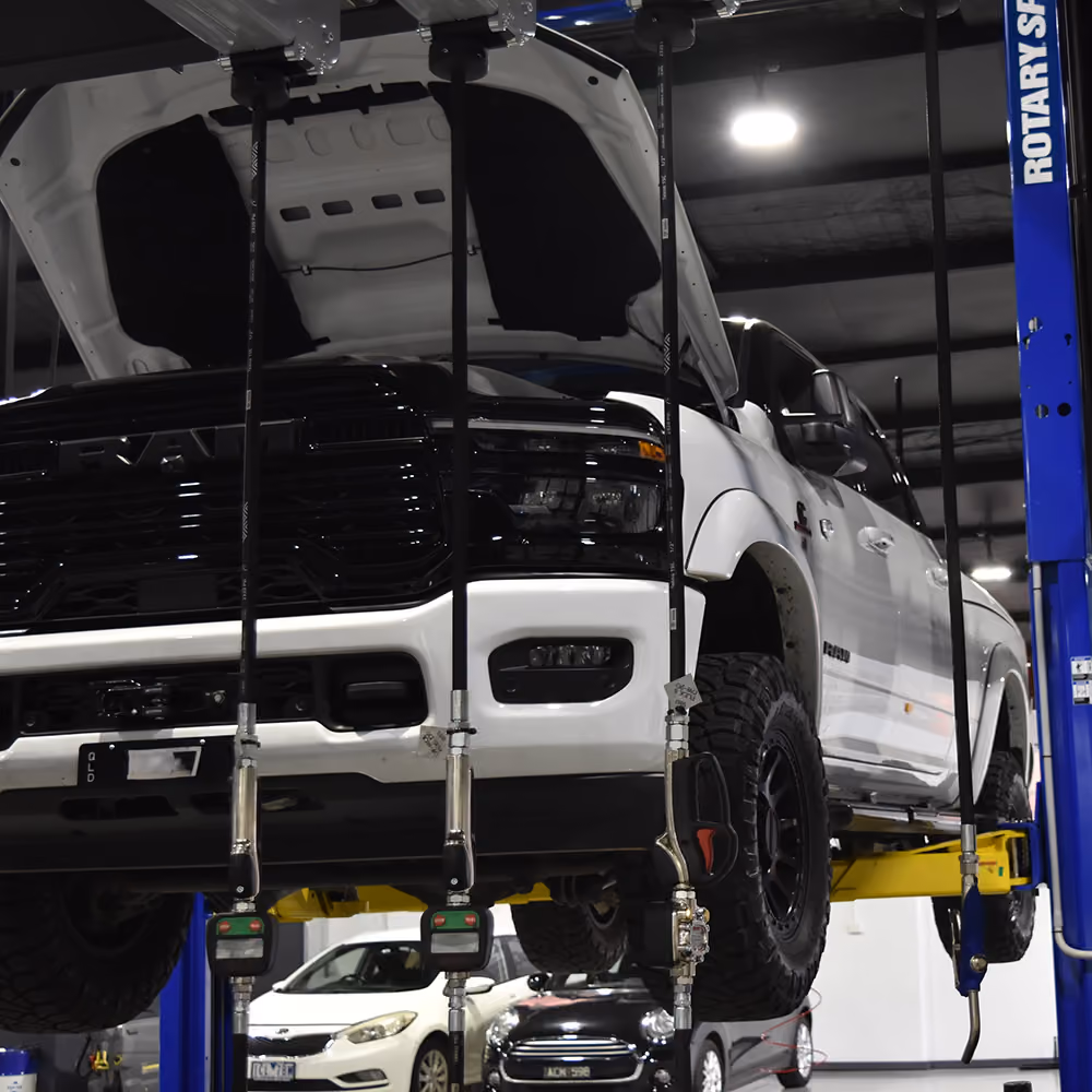 RAM truck raised on a workshop hoist during servicing.