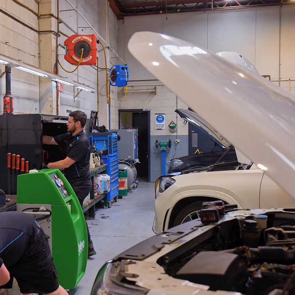 Technician preparing tools for car air conditioning repair and maintenance inside workshop.