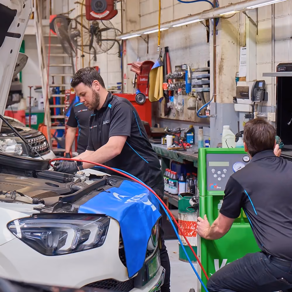 Mechanic diagnosing car air conditioning system using digital tools during inspection in Melbourne.