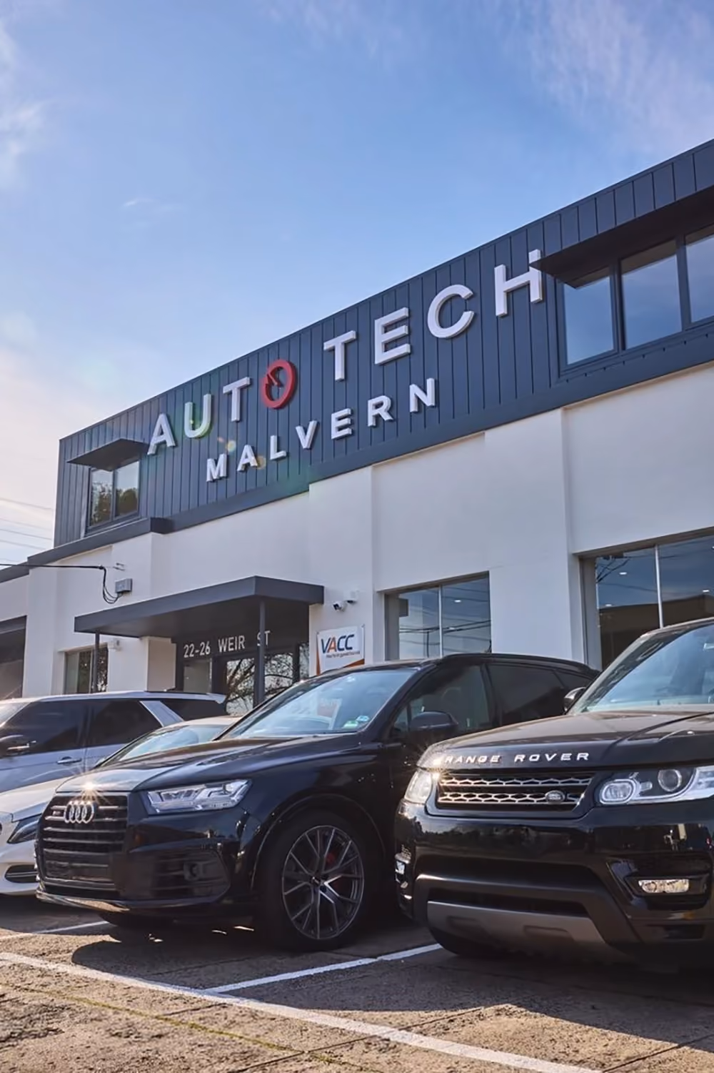 Auto Tech Malvern team standing together outside workshop with customer vehicles.