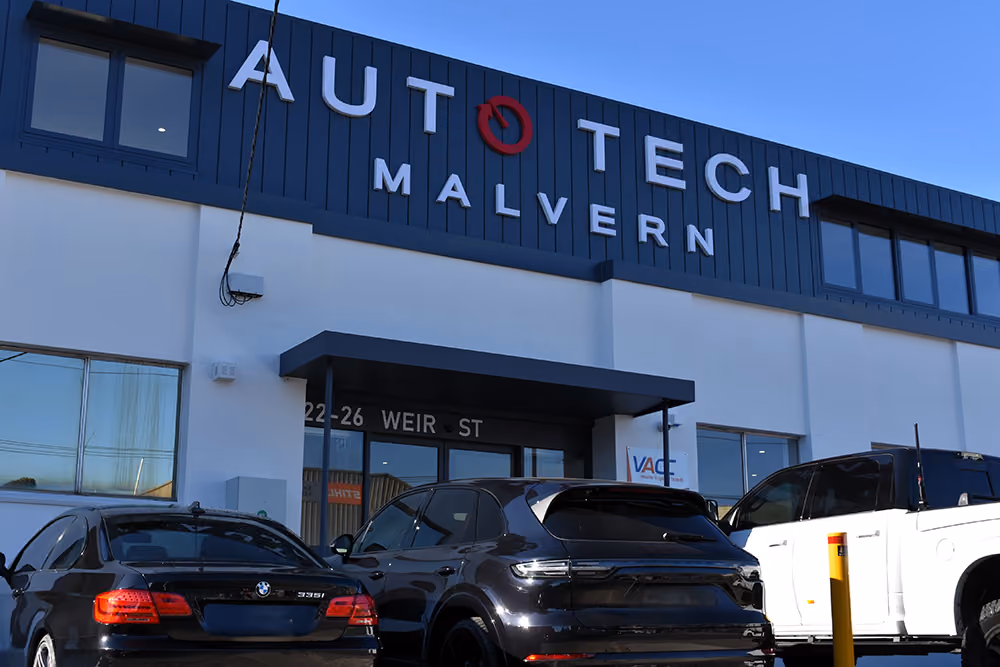 Auto Tech Malvern team standing together outside workshop with customer vehicles.