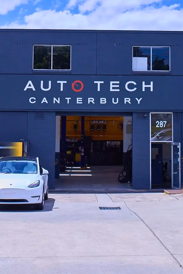 Exterior of Auto Tech Canterbury workshop with cars parked outside and open service bay.