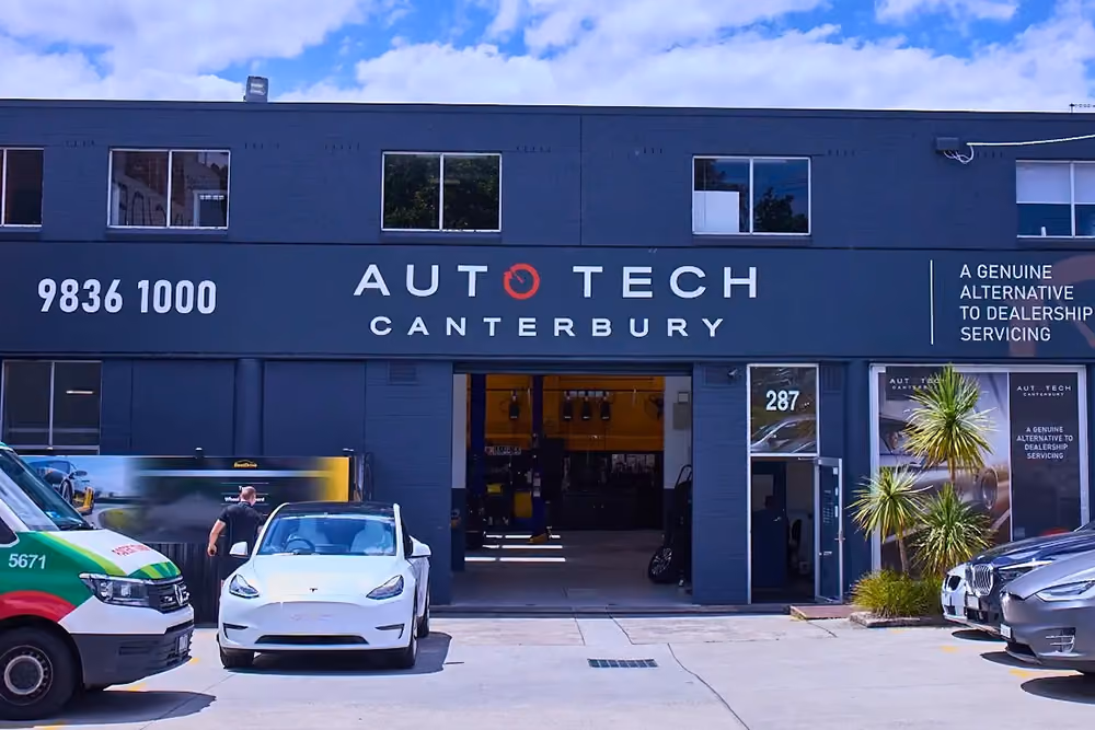 Exterior of Auto Tech Canterbury workshop with cars parked outside and open service bay.