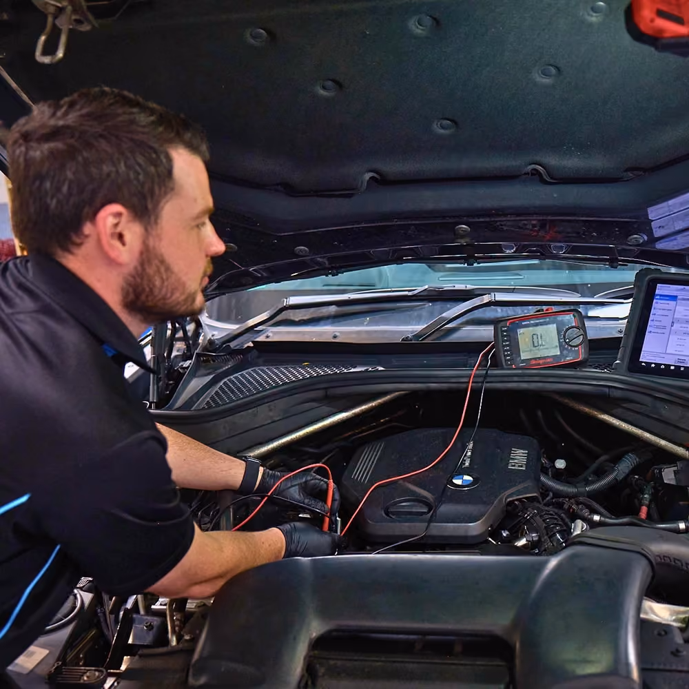 Technician performing a diagnostic inspection on a BMW during a European car service.