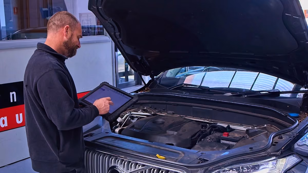 Technician performing a vehicle inspection with diagnostic software on a Volvo SUV.