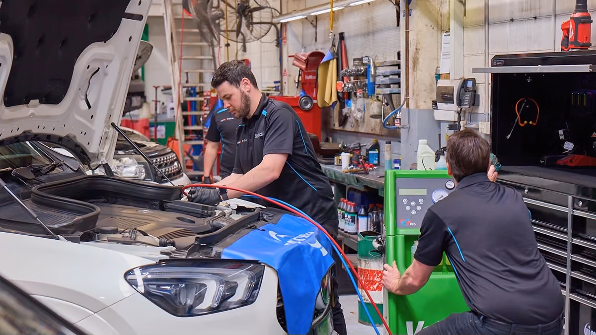 Technicians servicing a Mercedes-Benz using specialist diagnostic and air conditioning equipment.