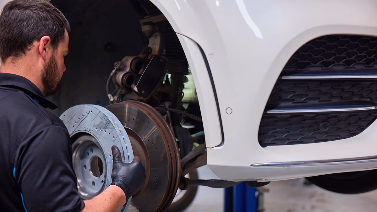 Technician replacing brake components during a scheduled prestige vehicle service.
