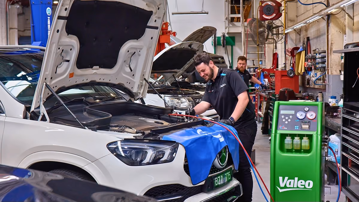 Technician performing a Mercedes-Benz service using specialist workshop equipment.