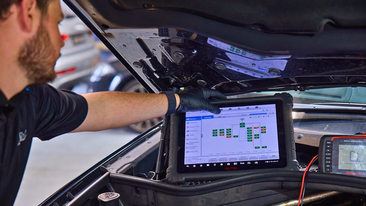 Technician using advanced diagnostic equipment to inspect a modern vehicle's electronic systems.