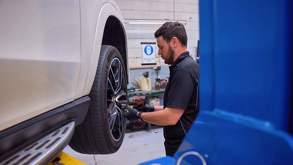 Auto Tech Group technician servicing the wheel assembly on a Land Rover SUV.
