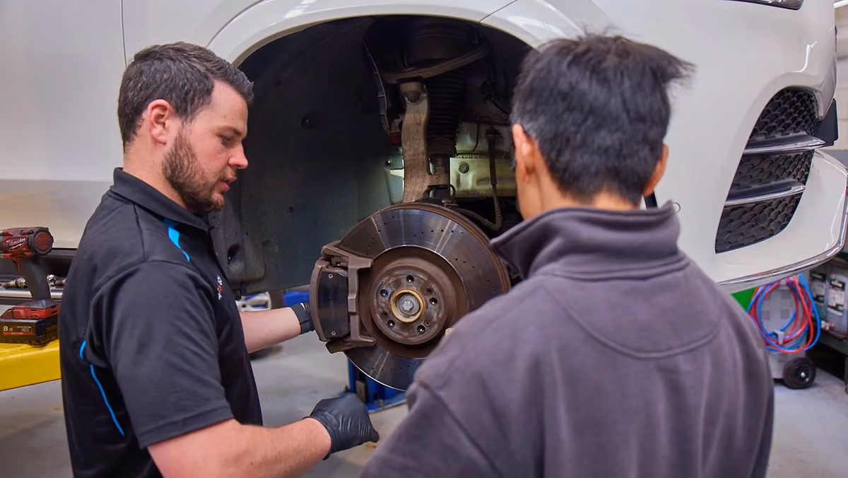 Technician explaining a Land Rover brake inspection during a vehicle service.
