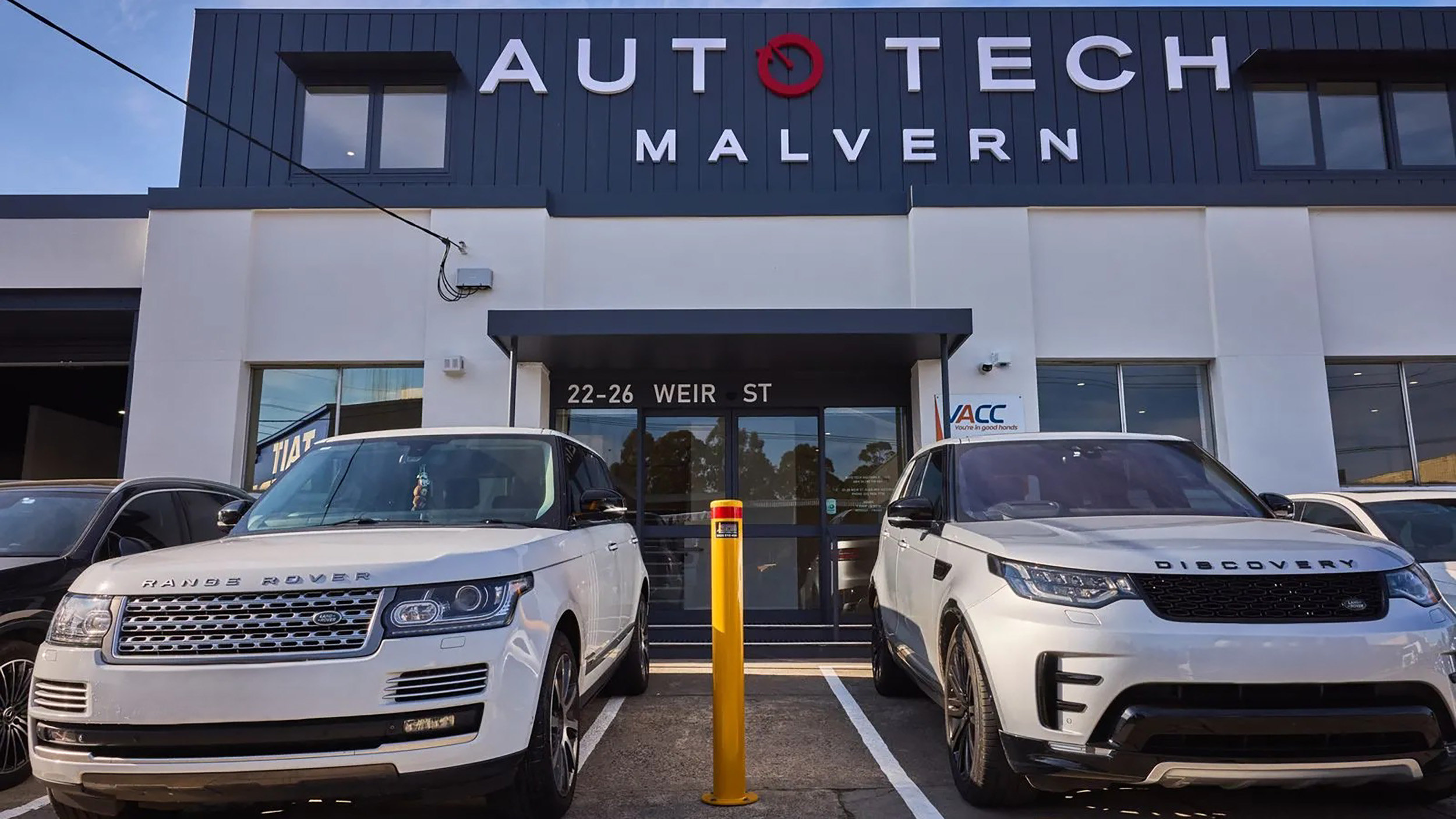 Land Rovers parked outside an Auto Tech workshop ready for servicing.