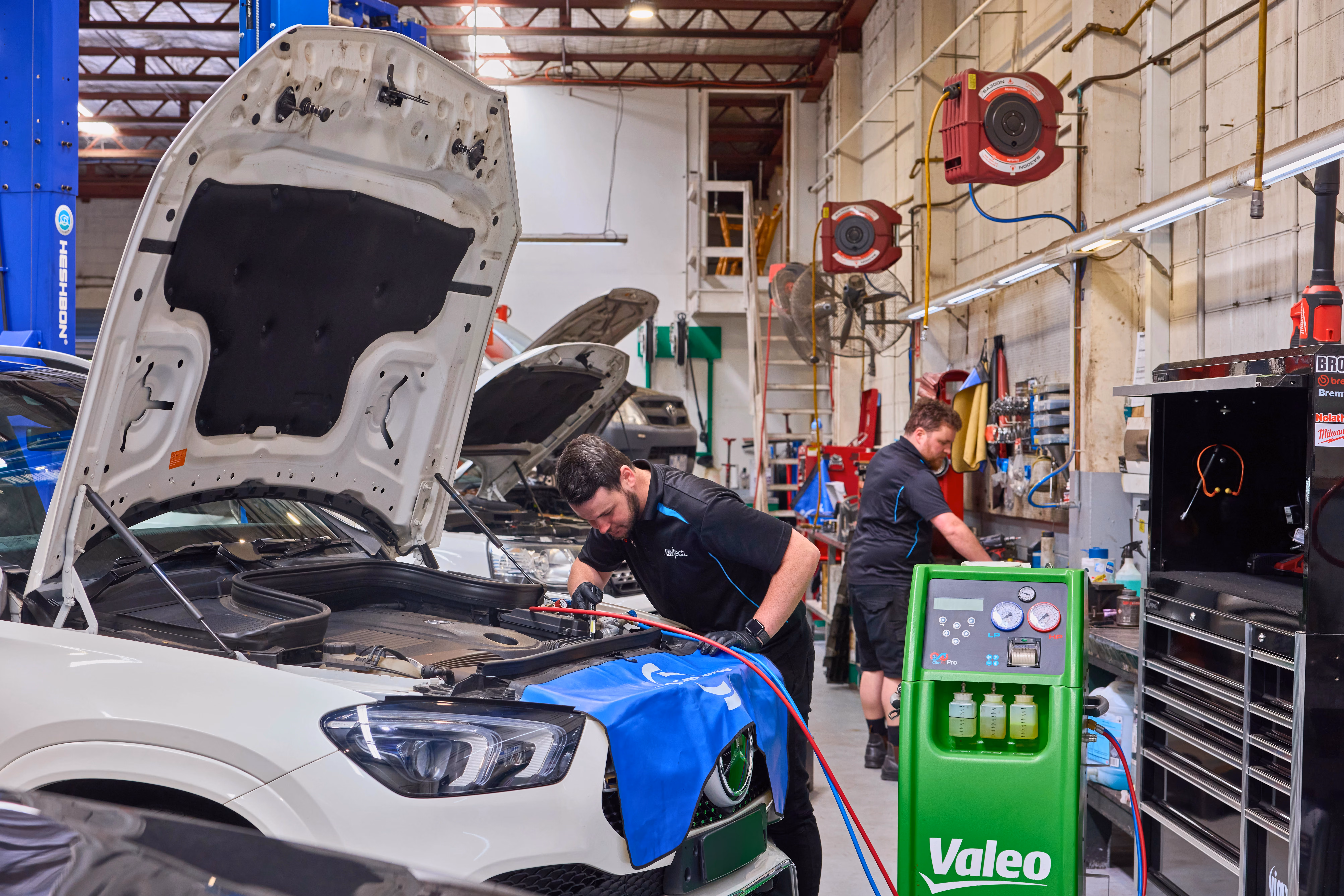 Technicians servicing a European vehicle in a specialist automotive workshop.