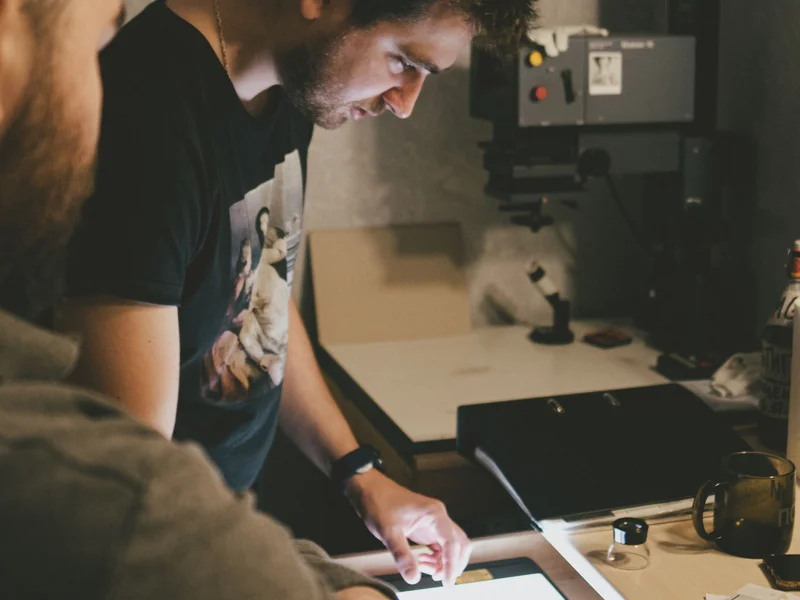Two people reviewing film negatives on a lightbox in a creative studio