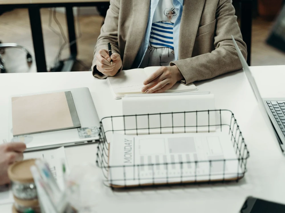 An executive assistant organizing a desk planner and notebook alongside a laptop