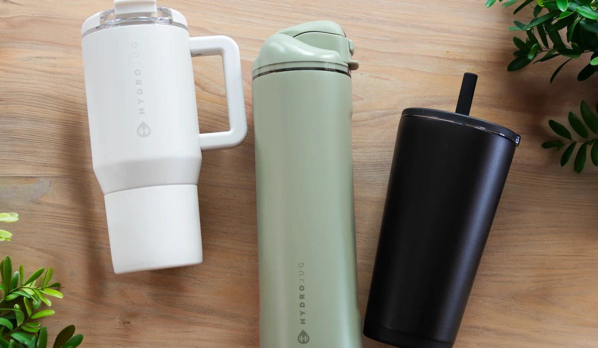 A flatlay of branded drinkware, a tumbler, bottle, and mug, styled as a curated welcome kit