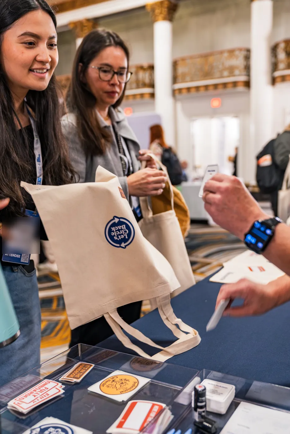 A smiling guest holding her finished tote with a Let's Circle Back patch
