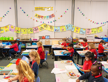 Young students in red uniforms working at desks in decorated classroom