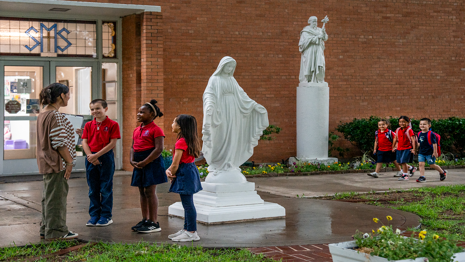 Students and teacher gathered near Mary statue outside SMS school