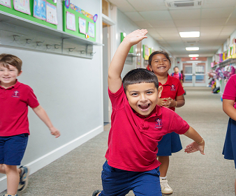 Students in red uniforms laughing and running through school hallway