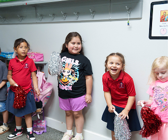 Students holding pom poms and smiling in a school classroom