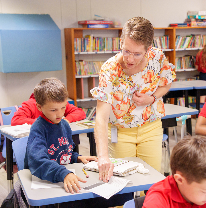 Teacher leaning over to assist a student at his desk