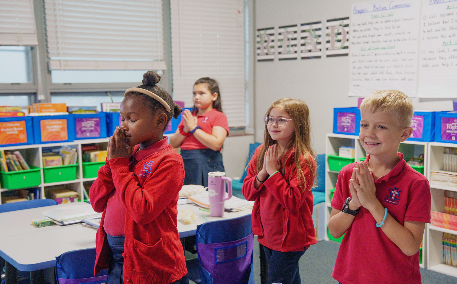 Students in uniform praying together in a Catholic school classroom