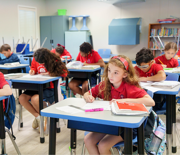Students in red uniforms working at desks in classroom