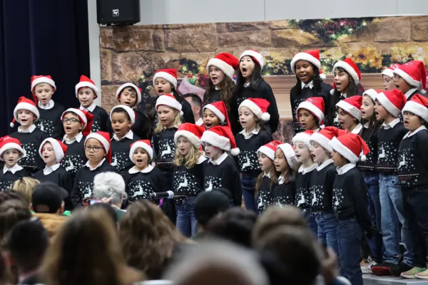 Elementary students in Santa hats performing holiday choir concert